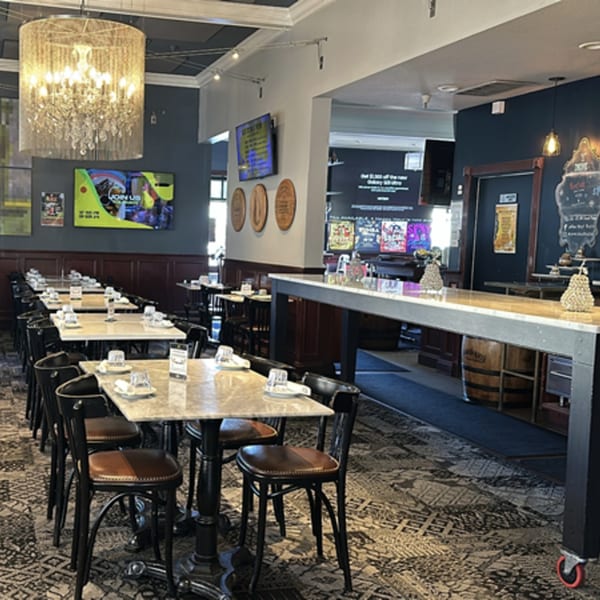 Interior of Pear Street Bistro with dining tables, chairs, a bar, and a large chandelier.