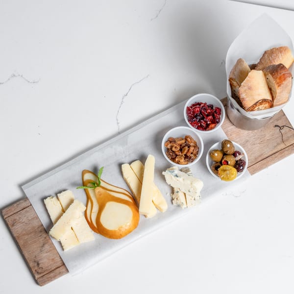 A charcuterie board with cheeses, candied pear, olives, nuts, dried cranberries, and bread.